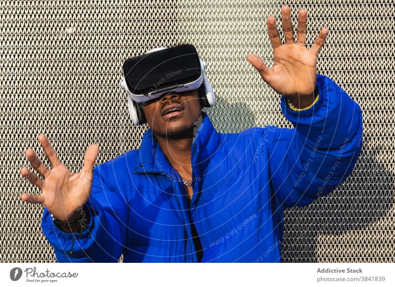 Black man experiencing virtual reality in city goggles vr glasses experience interact touch futuristic male ethnic black african american street metal fence