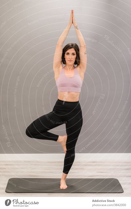 Slim woman in Tree pose on yoga mat vrksasana tree pose balance barefoot soul mindfulness stress relief female activewear content slender slim harmony home
