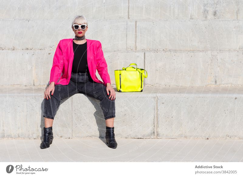 Stylish creative woman in pink jacket in city vivid style outfit model trendy color female bright yellow handbag cloth street sit cool urban vibrant fashion
