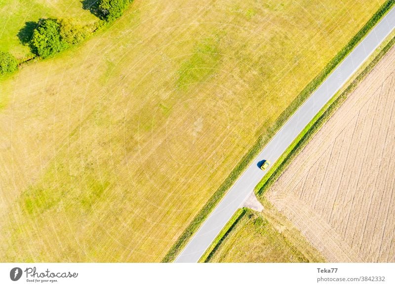 a yellow car on a country road in the summer from above td top down traffic countrsyside lone car from above concrete meadow