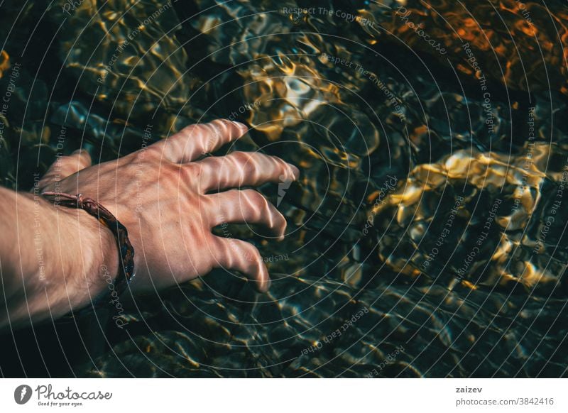 Close-up of a hand touching the surface of the water with light reflections human water surface water reflections undulations waves underwater caress aquatic