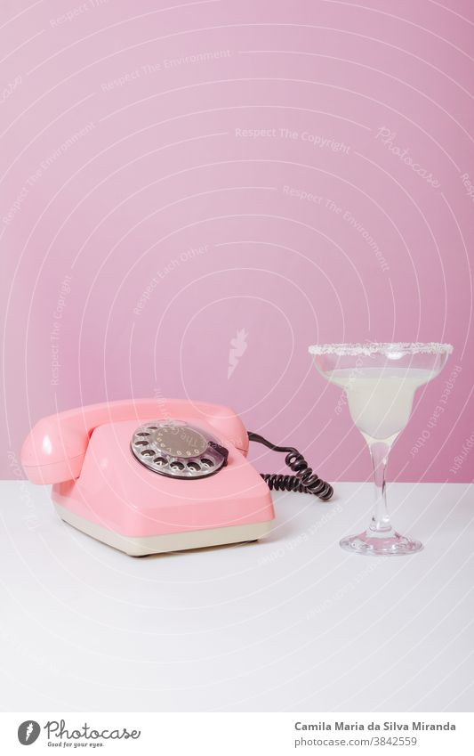 vintage rose phone with a drink beside it. 60's 60s advertise background call color copy space fifties for text fun funky good news isolated old fashion pink