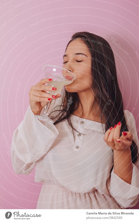 young woman drinking a cocktail - rose background adult alcohol beautiful beauty beverage cheerful closeup cool female girl glass hair happy health lifestyle