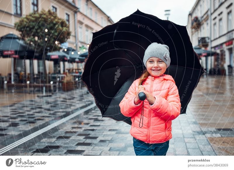 Little girl holding big umbrella walking in a downtown on rainy gloomy autumn day raining outdoors little seasonal fall childhood beautiful weather outside kid
