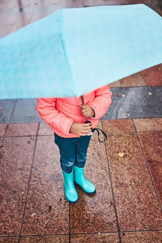 Little girl holding big blue umbrella during walk on rainy day raining outdoors cheerful joyful little autumn seasonal fall childhood happy beautiful weather
