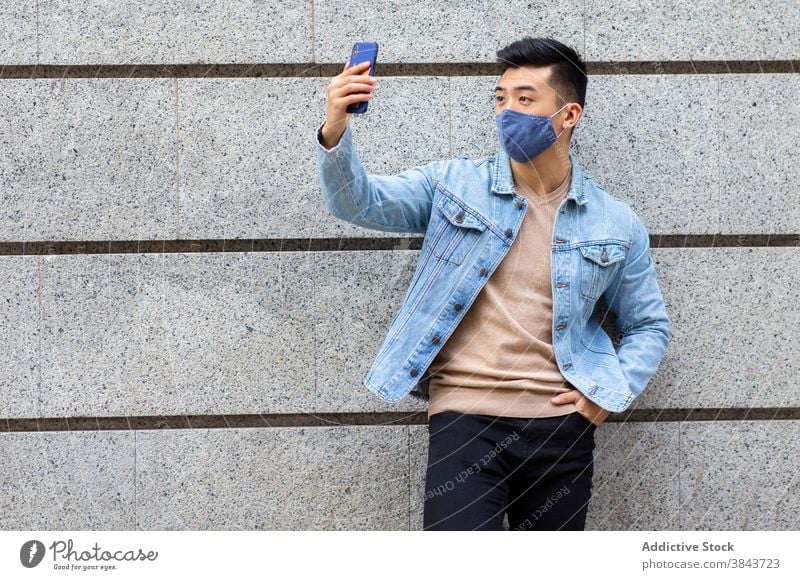 Ethnic man in mask taking selfie in city smartphone coronavirus covid 19 self portrait pandemic street male ethnic asian building medical protect device