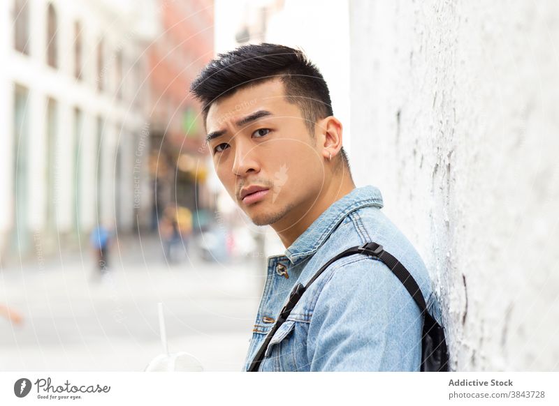 Young ethnic man standing on city street urban young asian serious hipster modern student casual male denim style confident trendy lifestyle handsome millennial