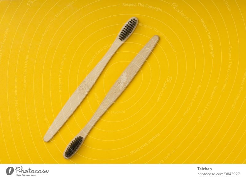 Two biodegradable wooden oral hygiene accessories on yellow background  . Zero waste, plastic free, sustainable lifestyle concept. Copy space , top view