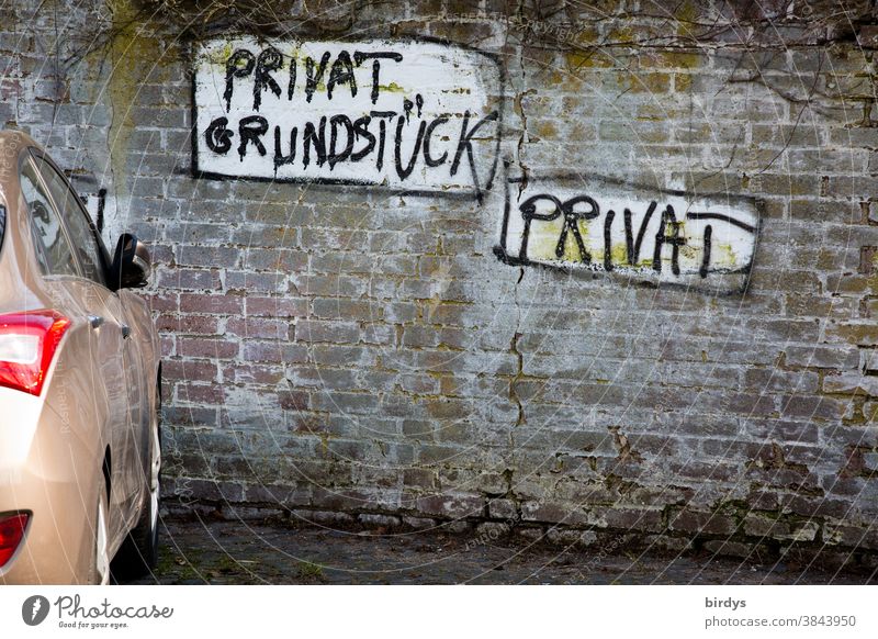 private parking place in front of an old brick wall with individual grafitti " private property, private " Characters graffiti Clue Parking Private Car car