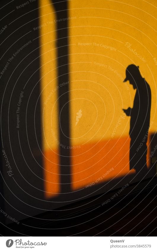 Shadow of a man with a mobile phone Cellphone communication Orange Wall (building) Telephone Lifestyle Mobile Technology technology Internet Modern