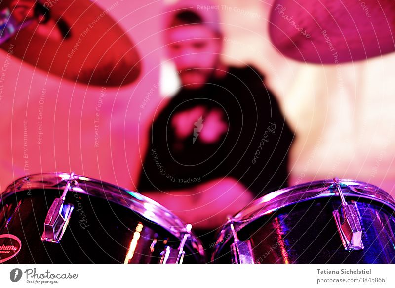 dimly discernible man playing drums. In the foreground you can see the toms and cymbals of the drums Drum set Musician play music Close-up music studio