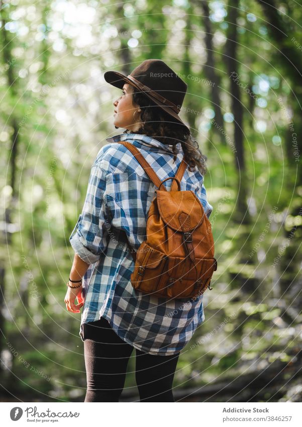 Traveling woman with backpack in forest wanderlust travel trip adventure admire enjoy explore style female checkered shirt leather trendy hat green woods nature