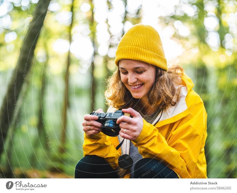 Cheerful woman with photo camera in woods photographer traveler yellow raincoat vacation explore enjoy cheerful female forest tourist holiday journey smile
