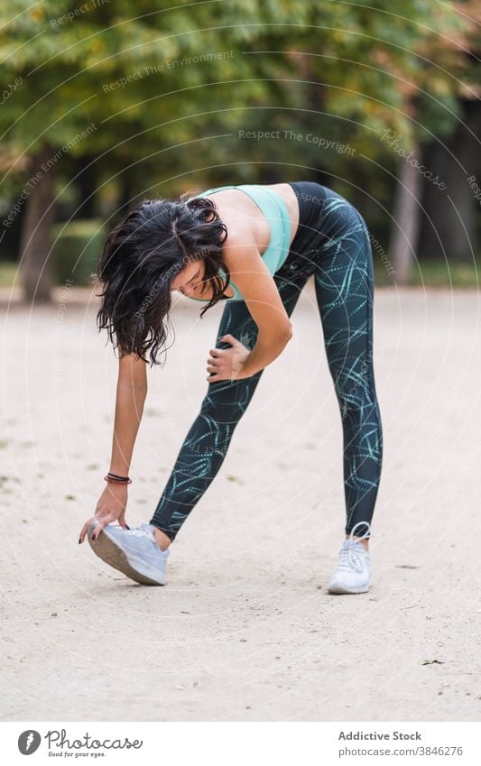 Cheerful sportswoman warming up during workout training exercise stretch park flexible slim female athlete fit sportswear wellness wellbeing body fitness