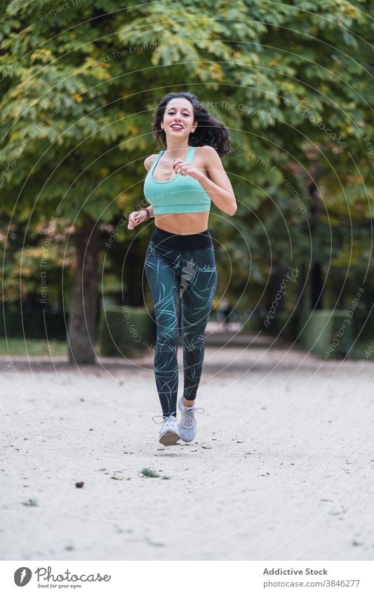 Young woman running in summer park runner training cardio endurance stamina slim sportswoman female path fit body fitness exercise wellness sportswear athlete