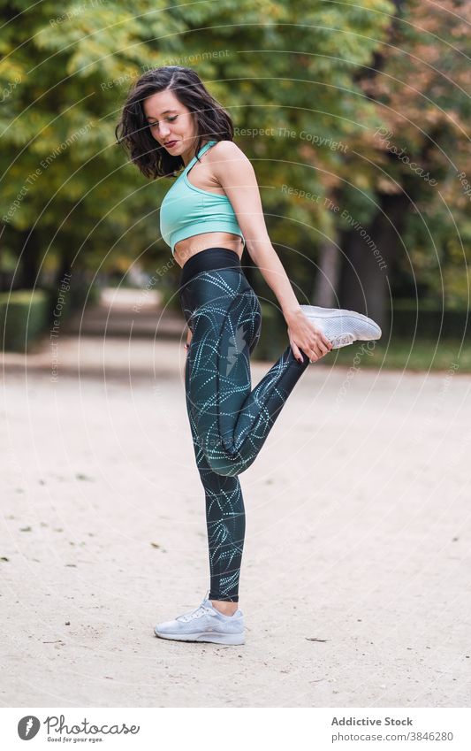 Cheerful sportswoman warming up during workout training exercise stretch park flexible slim female athlete fit sportswear wellness wellbeing body fitness