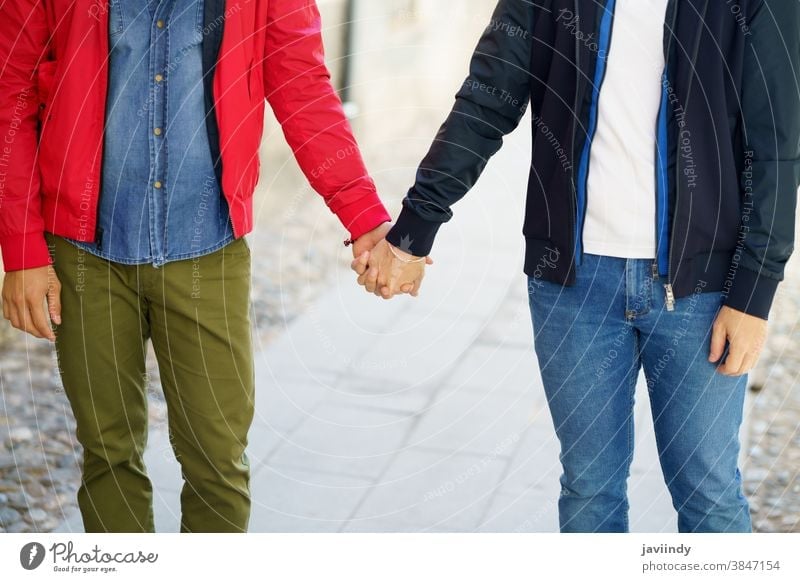 Gay couple holding hands in the street. gay men male love outdoors homosexual lgbt lgbtq relationship lovers boyfriend people adult outside urban background