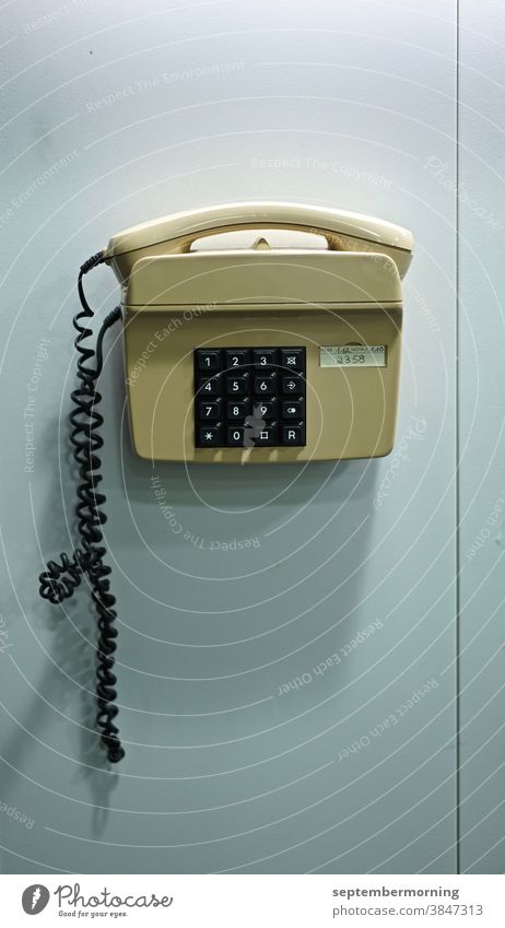 Phone on a wall key telephone Beige wall-mounted Deserted Interior shot Paste colours