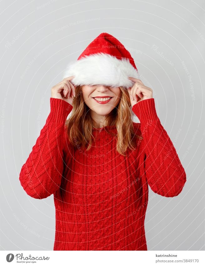 Young woman covering her eyes while touching santa hat hands Gift box christmas present smile white isolated red grey close up sweater Wrapped Holiday Package