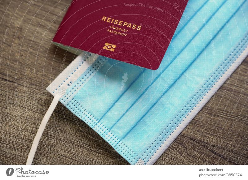 german passport reisepass and medical face mask - travel during corona covid pandemic new normal tourism health covid-19 coronavirus protection epidemic holiday