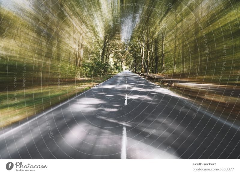 empty two-lane country road through woodland with motion blur street travel speed rural forest moving fast background woods nature tree-lined highway landscape