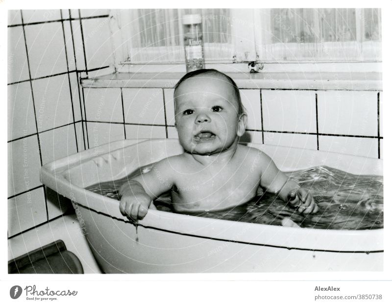 A small boy bathing in a plastic bathtub holds on to the edge and looks into the camera Baby Toddler Boy (child) 1 - 3 years neat Laundered Child Human being