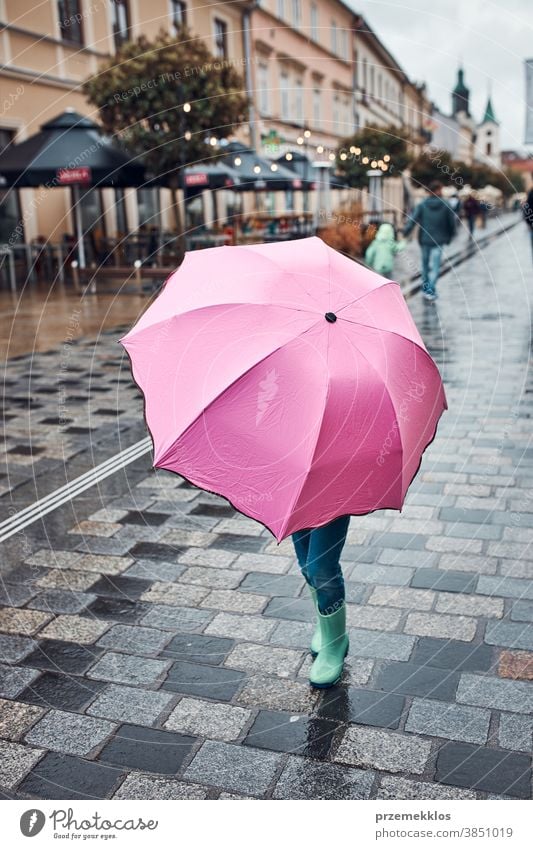 Child hiding behind big pink umbrella walking in a downtown on rainy gloomy autumn day raining outdoors little seasonal fall childhood beautiful weather outside