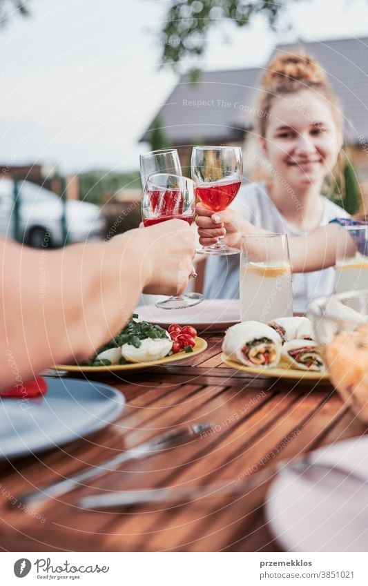 Family making toast during summer outdoor dinner in a home garden feast having picnic food man together woman barbecue table eating gathering people lifestyle