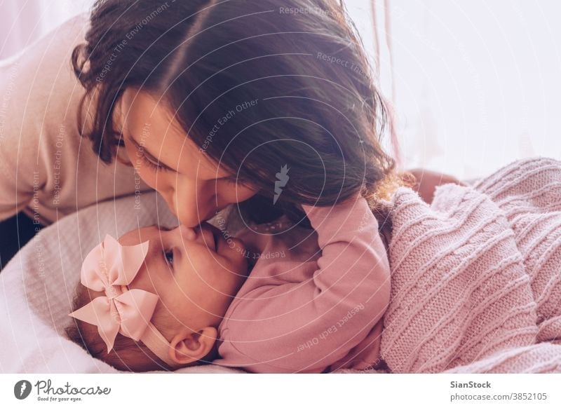 Young mother kissing her adorable baby girl. mom happy family kid child nose playing loving beautiful portrait happiness young love daughter little white cute