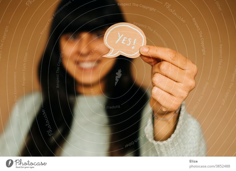 Woman holding a speech bubble with Yes written on it. Approval Joy communication yes Positive Optimism Speech bubble authored English Enthusiasm Communicate