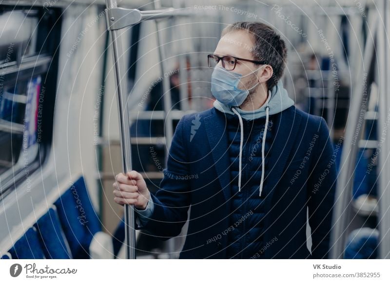 Prevention in public transport, health awareness for pandemic protection. Young man wears medical mask while travels by urban train, protects himself from virus. Covid-19 outbreak in Europe.