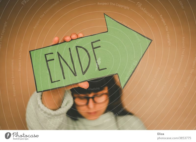 Woman holding a green arrow with the word end End over from over and done Transience Divide Past Quit Green Arrow authored Suicide Suicidal tendancy Exit route