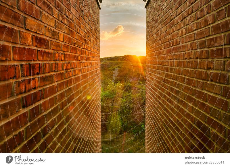 Golden Sunrise and Landscape Between Brick Walls brick landscape narrow sunrise golden opening light at the end of the tunnel rolling landscape concept hope