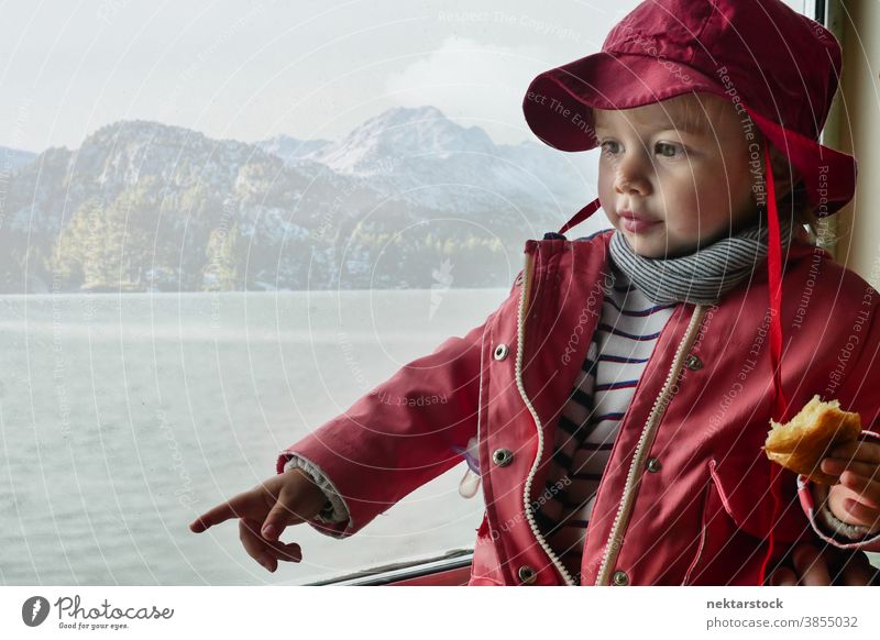 Toddler Looking Away and Pointing on Mountain and Lake Background child toddler 2 years old caucasian portrait indoor cute childhood small coat hat pointing
