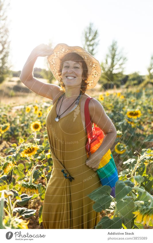 Tranquil woman relaxing in sunflower field enjoy nature bloom season sunny carefree female rainbow bag stand calm weather tranquil eyes closed peaceful freedom