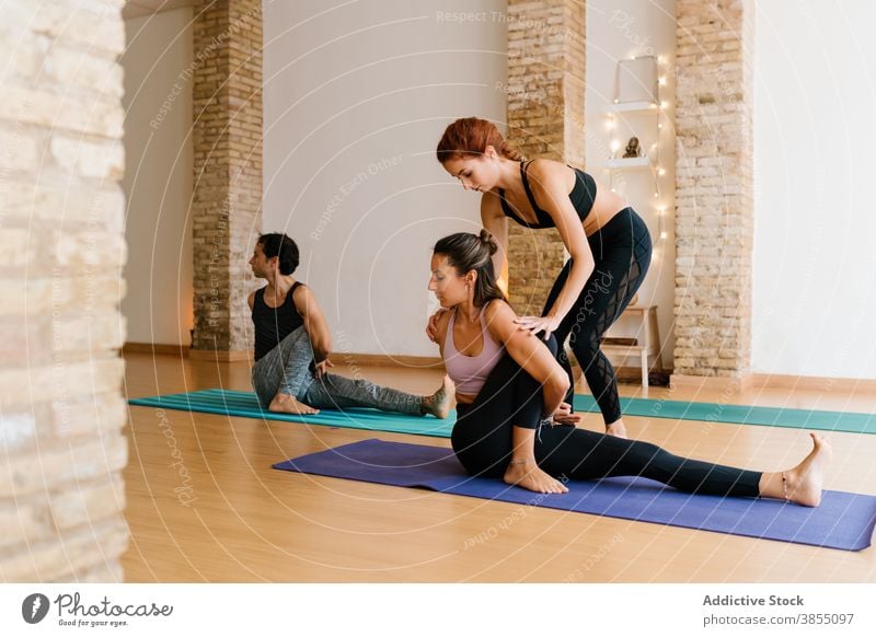 Coach helping woman with Sage Marichis pose women yoga stretch lesson studio instructor sage marichis pose twist young female fit slim practice healthy wellness