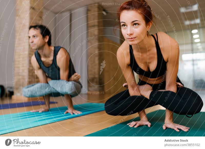 Man and woman doing Scale pose balance yoga practice studio together group scale pose sportswear slim healthy wellness asana adult young physical flexible fit