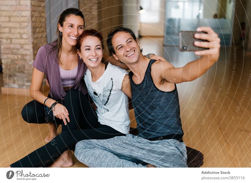 People taking selfie during yoga lesson man women together studio smile smartphone hug break group happy cheerful relax embrace rest gadget joy device optimist