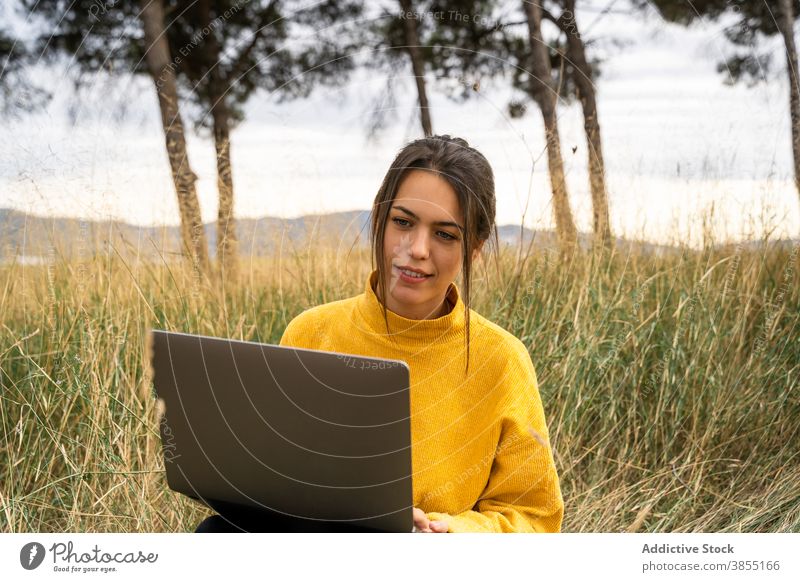 Thoughtful woman working on laptop in meadow freelance remote field countryside project autumn female blanket job internet pensive gadget computer busy watch