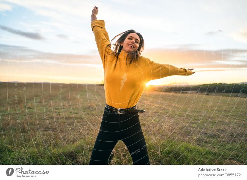 Cheerful woman jumping in field at sunset carefree freedom enjoy smile moment countryside female outfit casual meadow rural area active happy autumn fall season