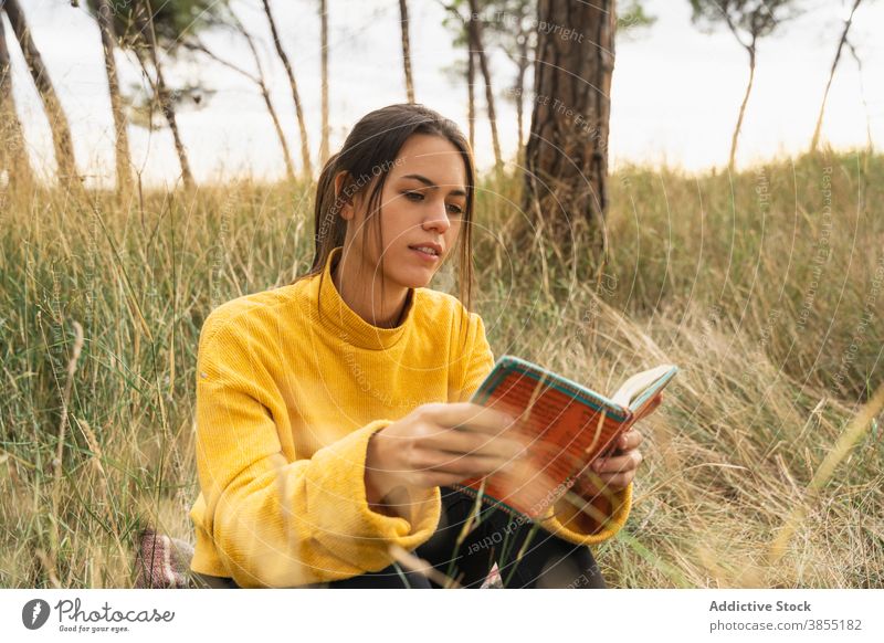 Serene woman reading book in meadow autumn enjoy relax literature story interesting carefree female hobby knowledge sit peaceful novel pleasure serene fiction