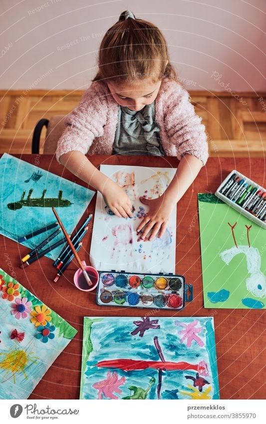 Little girl preschooler painting a picture using colorful paints and crayons child dye education art home paper childhood creation craft table creativity kid