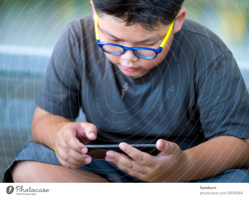 Asian boy have a serious face while playing game on smartphone child sweat asian kid children hand glasses technology telephone perspiration young earnestly