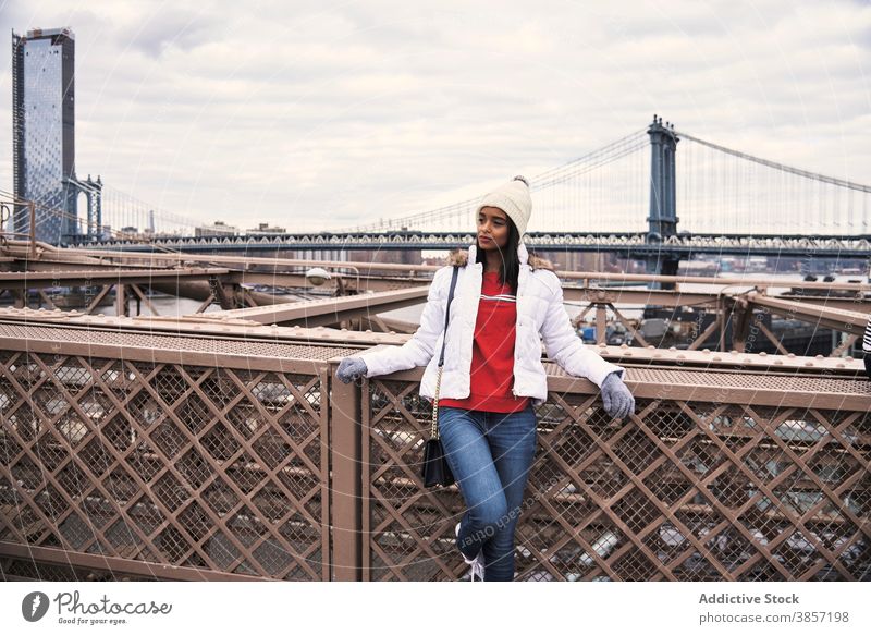 Ethnic woman relaxing on bridge in city stroll enjoy warm clothes outerwear season outfit style female ethnic african american black new york usa united states