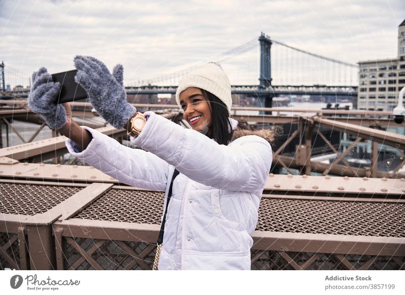 Smiling ethnic woman taking selfie in city smartphone warm clothes outerwear season cheerful self portrait using female black african american new york
