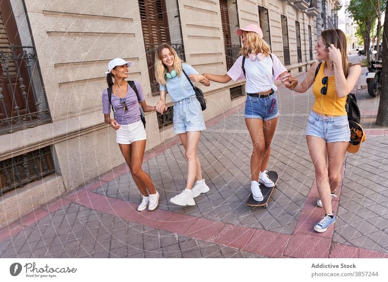 Happy teen girlfriends walking on city street group teenage having fun happy together cheerful skateboard urban multiracial multiethnic diverse chat friendship