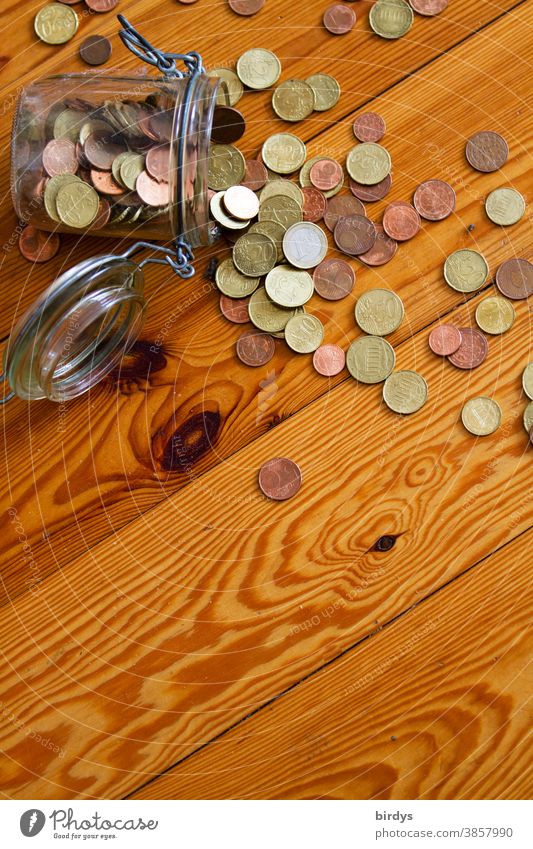 Cashier's check. Saved small change from a jar lies poured out on a wooden floor savings Euro Coins Poverty Glass euro cents Coinage rotten cost of living