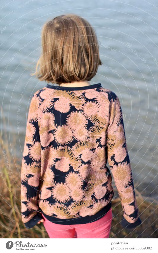Girl stands on the shore and looks at a lake. Rear view. Relaxation, enthusiasm, curiosity. Childhood Lake bank reed curious Nature Sweater Pattern Back averted