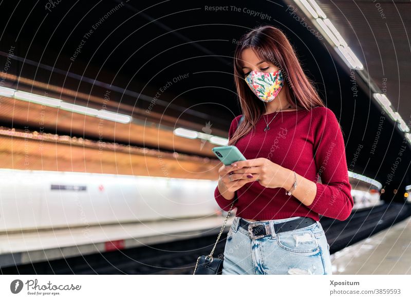 Young woman using smartphone at train station portrait mask face lifestyle platform modern public technology transport caucasian passenger people transportation