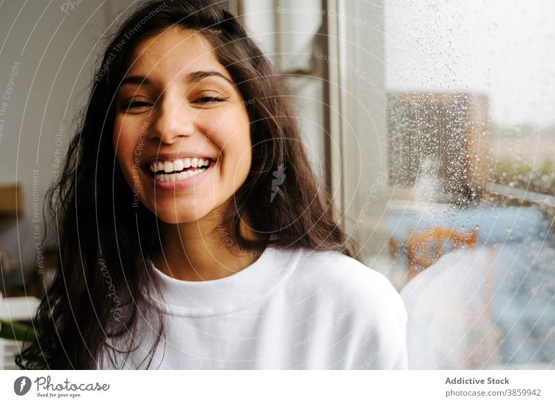 Peaceful woman standing at window with waterdrops raindrop mood droplet peaceful tranquil ethnic female tender calm solitude lonely alone gentle charming serene